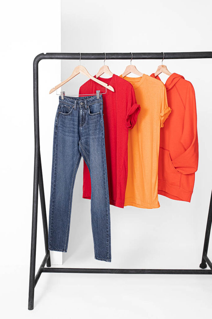 Garments made with Infinna created from 100% regenerated post-consumer textile waste. From left to right: Jeans – 50% Infinna/50% cotton; red T-shirt – 50% Infinna/50% cotton; orange T-shirt – 100% Infinna; orange hoodie – 75% Infinna/25% cotton. Photo courtesy Infinited Fiber Company/Satu Mali