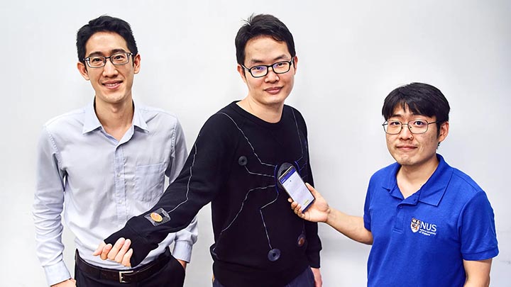 A smartphone-powered suit, pictured here with a design that resembles the motif on a Spider-Man’s suit, designed by a team led by Assistant Professor John Ho (left) and the research team of Dr Lin Rongzhou (center) and Dr Kim Han-Joon (right). Photo courtesy National University of Singapore